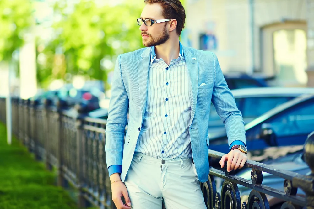Stylish man in a blue suit leaning on a railing