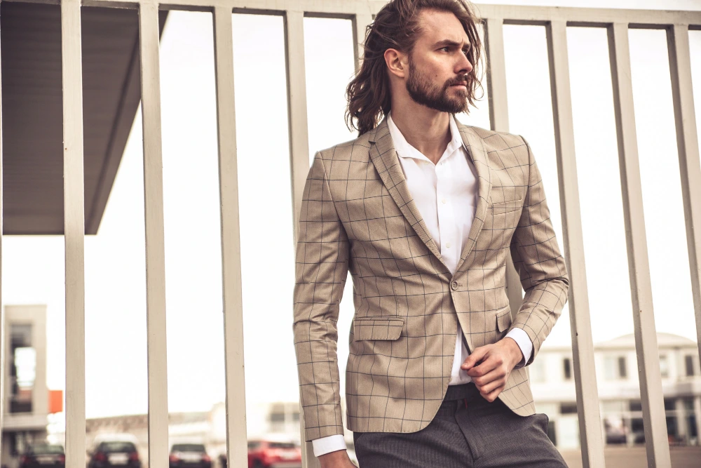 Man in stylish Tan and Khaki suit near fence